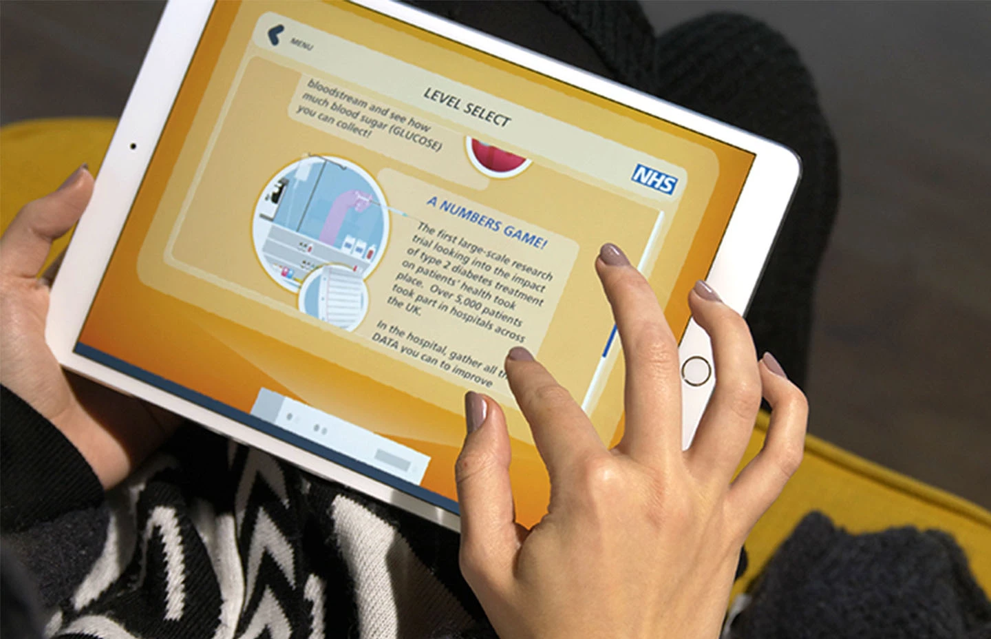 Person holding tablet and interacting with NHS Rebo's Adventure app