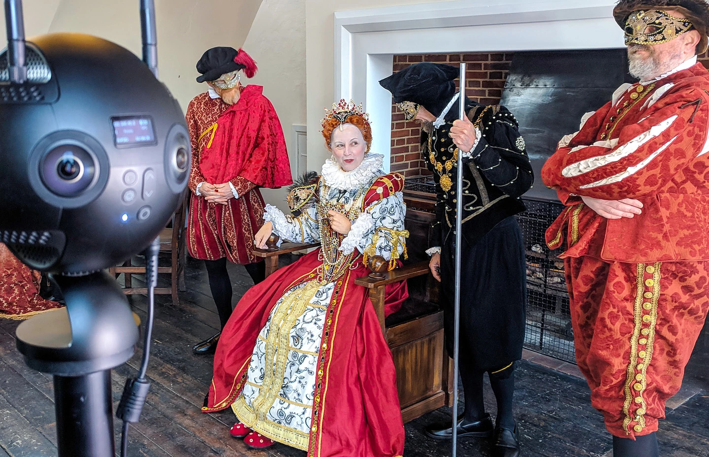 Elizabeth the First flanked by servants sat on a throne
